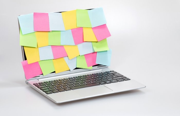 Laptop covered in blue, pink, green, and yellow post it notes. Blog post featured image.