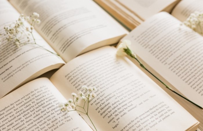 Four open books with small white flowers on and between them. Blog post featured image.