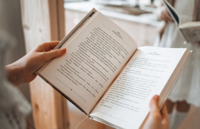 Woman in a white dress holding an open book. Blog post featured image.