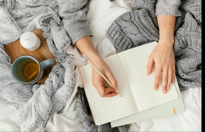 Woman lying in bed writing in a notebook